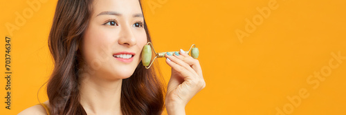 Beautiful young Asian woman using jade face roller, massager the skin of the face