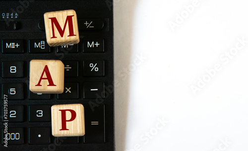 MAP - acronym on wooden cubes against the background of a calculator and paper clips. Copy space
