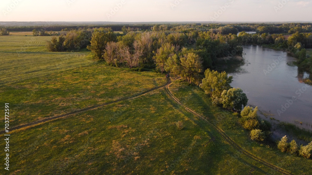 a river, a green field with trees and a country road a river, a green field with trees and a country road