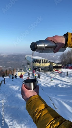 First person POV shot: traveller pours the hot tea at the mountains infront of the snowy peaks on sunny day