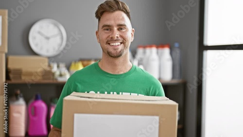 Smiling man holding donation box in storage room with shelves of supplies. photo