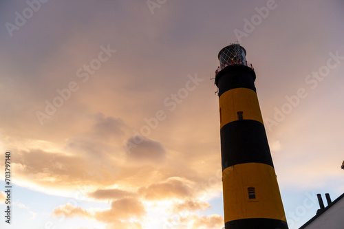 imagen del St John's Point Lighthouse con las luces del atardecer y el cielo con algunas nubes. 