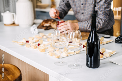 Wine Tasting Preparation with Cheese Pairings. Sommelier prepares for a wine tasting event, carefully pairing various cheeses with wines, featuring an unopened bottle and elegant glasses. photo