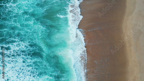 Drone shot turquoise sea waves washing empty tropical beach. Foamy ocean water.