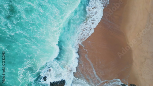 Turquoise sea waves crashing on sandy coast aerial view. Ocean washing seashore photo