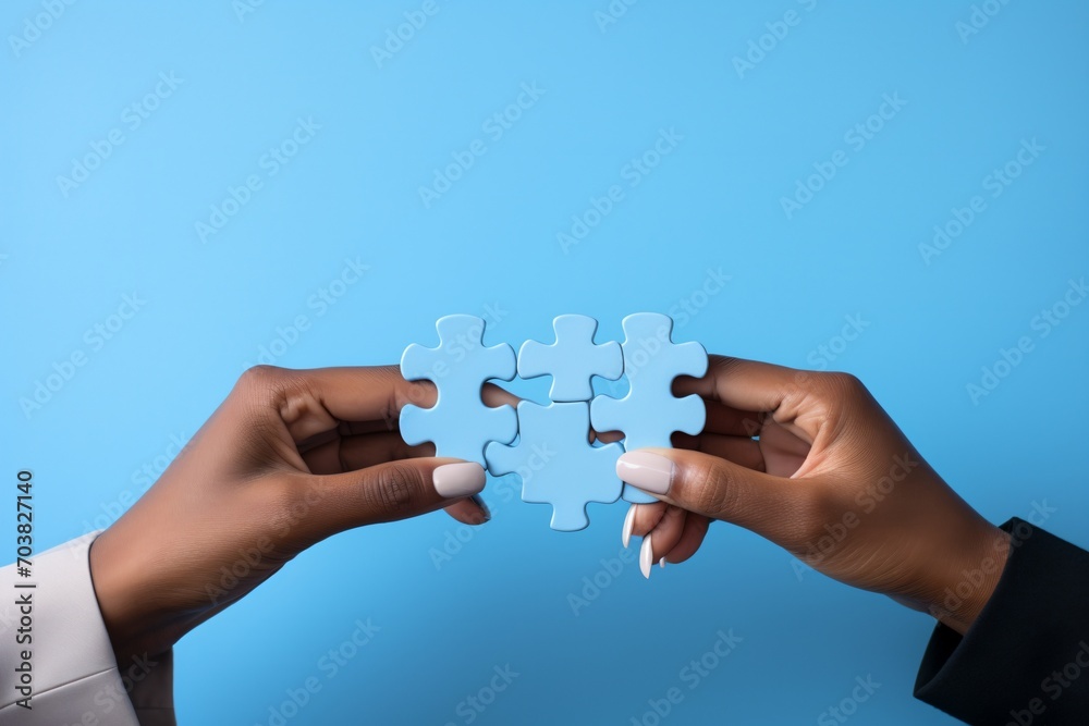 Blue puzzle pieces being put together by two black hands on a blue background, Blue puzzle pieces being put together by two black hands on a blue background,