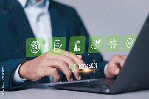 ISO 14001 concept. Businessman use laptop with ISO 14001 certified for environmental management systems (EMS). Identify, control and reduce the environmental impact of activities.