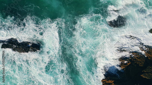 Aerial view waves breaking at coastal rocks in slow motion. Dramatic foamy sea