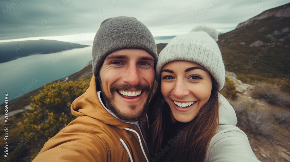 Happy couple taking selfie on top of the mountain