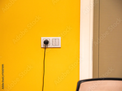 Tableau sur toile Gray electrical socket on yellow wall and charger plugged into the socket at working room