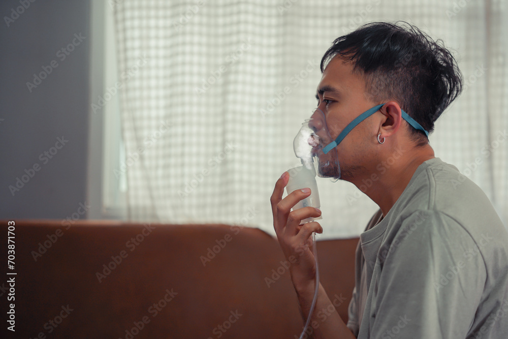 Asian boy wearing oxygen mask. man using asthma inhaler while sitting at home due to allergy. Asia man using spray asthma.
Asian boy wearing oxygen mask. man using asthma inhaler while sitting at home due to allergy. Asia man using spray asthma.