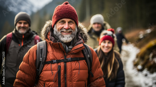A group of elderly people are hiking together through the forest and mountains on a winter day
