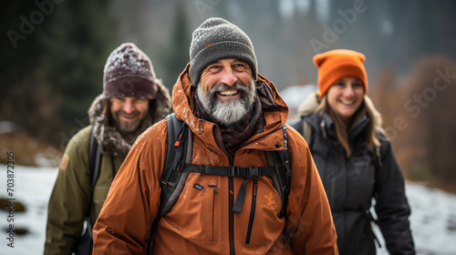 A group of elderly people are hiking together through the forest and mountains on a winter day