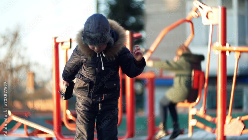 Child toddler ukrainian caucasian boy in warm winter clothes playing in a cold snowy puddle Child toddler ukrainian caucasian boy in warm winter clothes playing in a cold snowy puddle