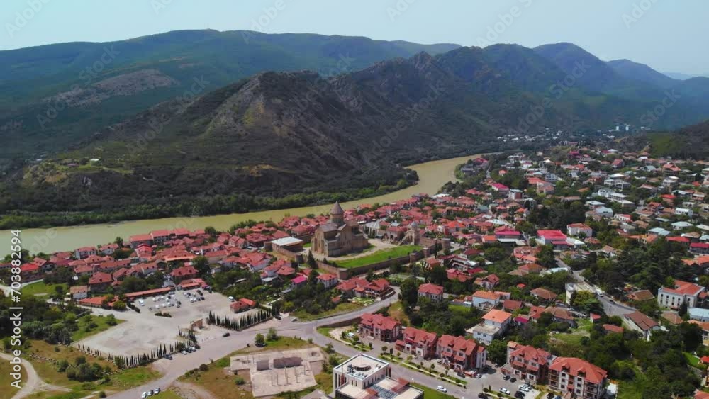 Beautiful aerial view of streets of Mtskheta village in Georgia. Mtkvari river. Summer sunny day. Travel and vacation. Svetitskhoveli Cathedral fortress in the center. Beautiful aerial view of streets of Mtskheta village in Georgia. Mtkvari river. Summer sunny day. Travel and vacation. Svetitskhoveli Cathedral fortress in the center.