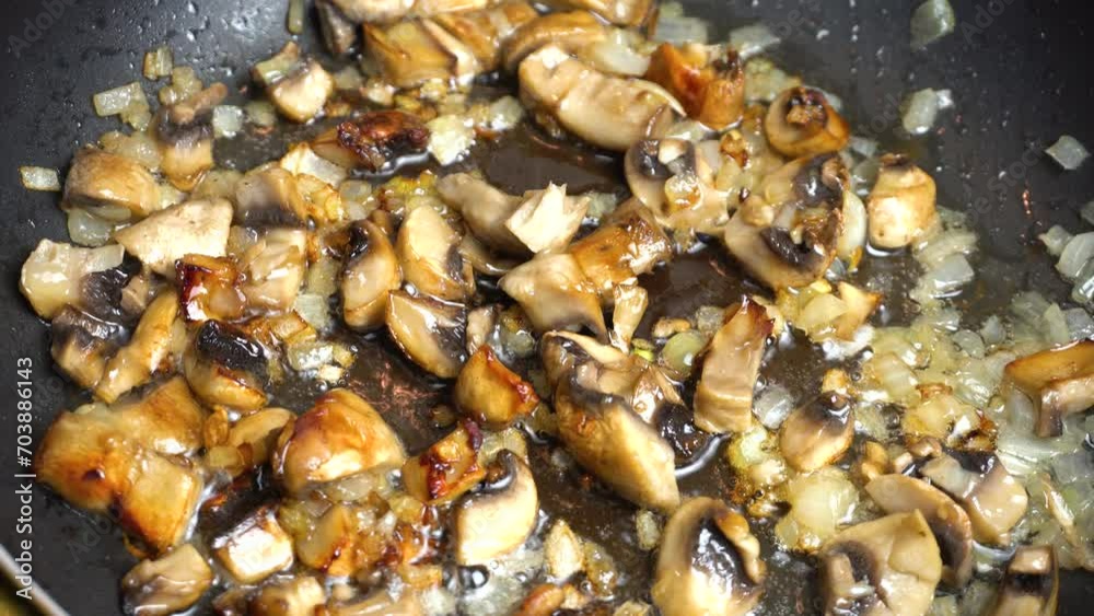Mushrooms and onions are fried in a frying pan in sizzling oil. Close-up. Step-by-step video recipe. Cooking master class.