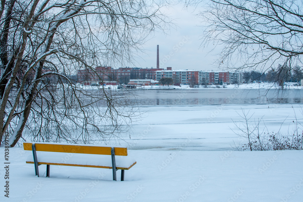 Yellow bench in a park near the lake overlooking the city in Tampere, Finland during a cold winter day