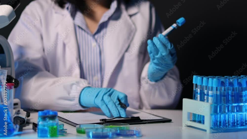 Scientist analyzes a colored liquid to extract the DNA and molecules in the test tubes. Scientists test the chemical reactions of the solution and test biological fluids in test tubes. Scientist analyzes a colored liquid to extract the DNA and molecules in the test tubes. Scientists test the chemical reactions of the solution and test biological fluids in test tubes.