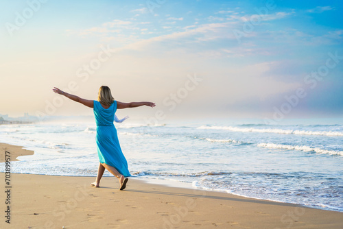 Beautiful mid adult woman walking on sunny beach 