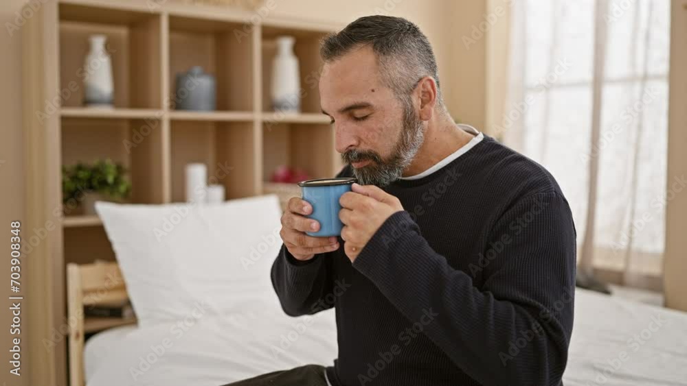 A mature man with a beard enjoys coffee in a cozy bedroom setting, creating a peaceful morning atmosphere. A mature man with a beard enjoys coffee in a cozy bedroom setting, creating a peaceful morning atmosphere.