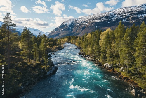 Drone high-angle photo of the turquoise-colored mountain river flowing in the pine woodland with a view of the mountain peaks in the background in Innlandet County, Norway photo