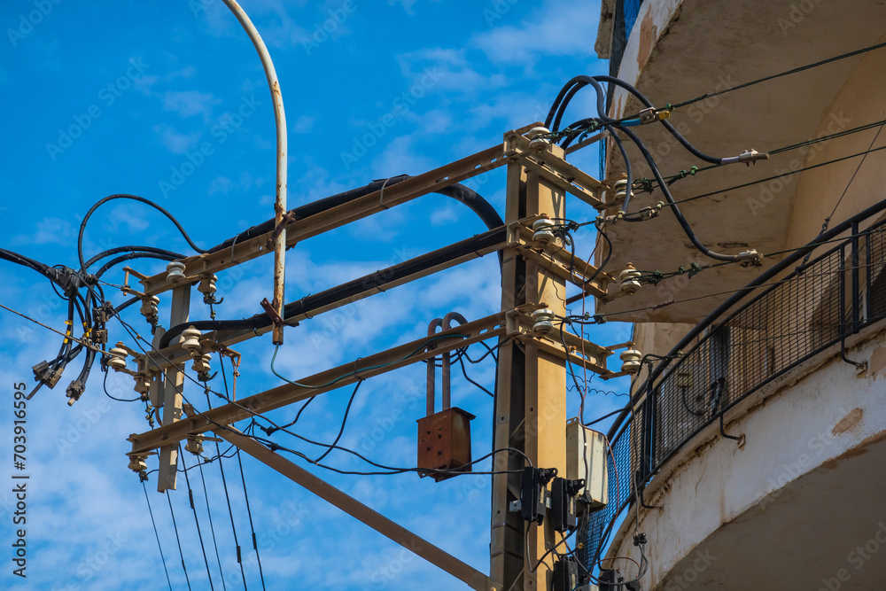 Complex web of power lines and transformers against a clear blue sky Complex web of power lines and transformers against a clear blue sky