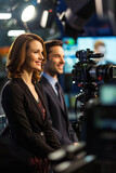 Man and woman TV presenters anchor the news in a television news studio.