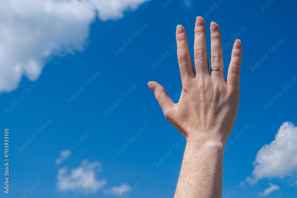 beautiful open hand with a ring. Sky background with clouds beautiful open hand with a ring. Sky background with clouds