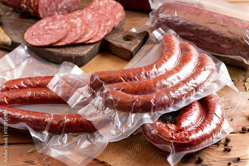 Dried sausage in vacuum package on wooden table