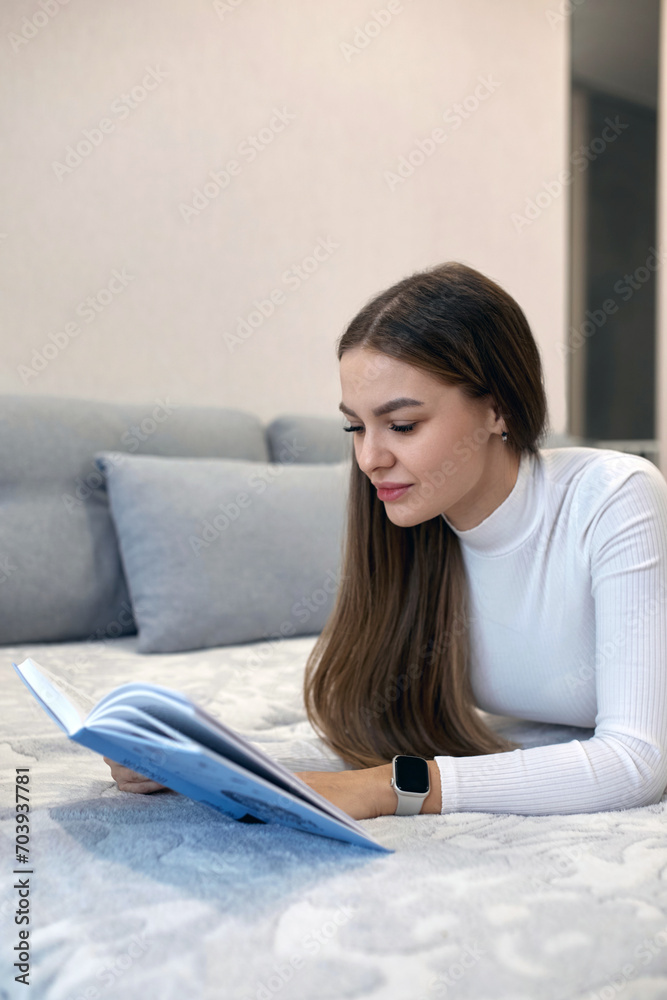 Beautiful sexy adult woman spends her weekend in a comfortable bedroom, lying on the bed, reading a book and enjoying classic literature. Beautiful sexy adult woman spends her weekend in a comfortable bedroom, lying on the bed, reading a book and enjoying classic literature.
