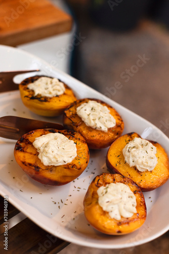 Grilled tasty cut peaches, served with whipped cheese cream, closeu
