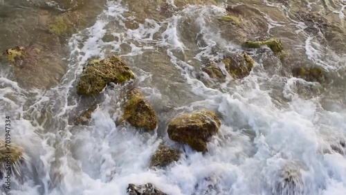 Sea waves lapping below with a lot of foam. stones and rocks in water.