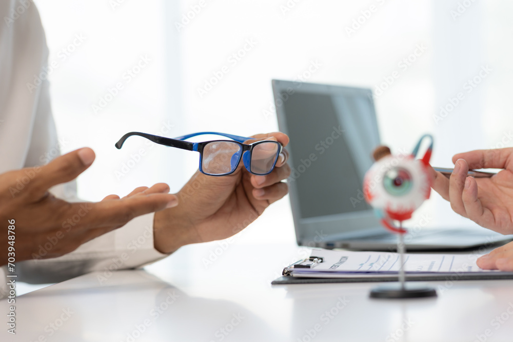 Close-up of an Asian male doctor showing an eyeball model and explaining eye diseases to a male patient in hospital. health care concept Close-up of an Asian male doctor showing an eyeball model and explaining eye diseases to a male patient in hospital. health care concept
