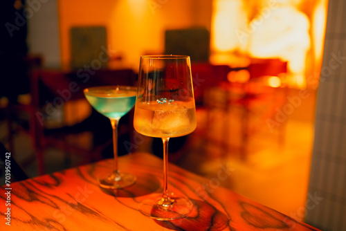 Two delicious ice cold cocktails in exquisite glasses stand on a wooden table in a restaurant. photo