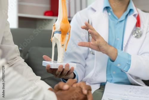 Male doctor and male patient discussing knee joint model It is likely that the focus will be on the condition of arthritis in the knee during a medical consultation at a hospital or clinic. medical he