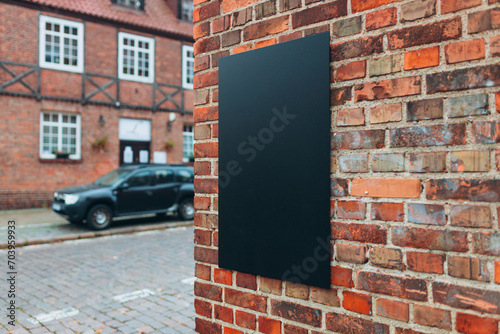 Blank black billboard sign mockup in the urban environment. Clear urban glued advertising canvas. Billboard advertisement advertiser on textured red wall