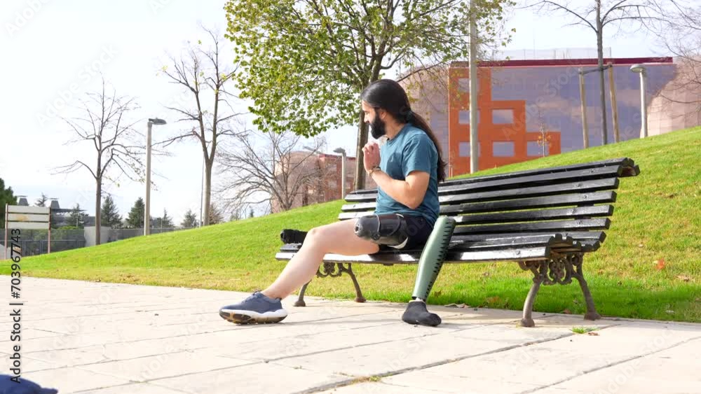Physically disabled man adjusting prosthetic leg before running sitting on an urban park bench Physically disabled man adjusting prosthetic leg before running sitting on an urban park bench