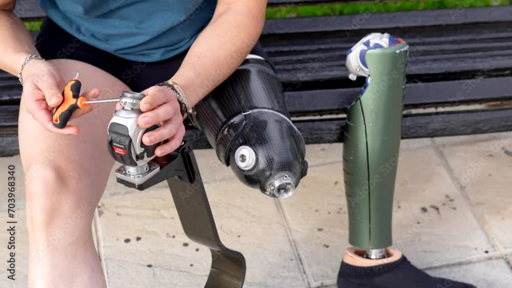 Close-up of a man adjusting his artificial leg sitting on a park bench Close-up of a man adjusting his artificial leg sitting on a park bench