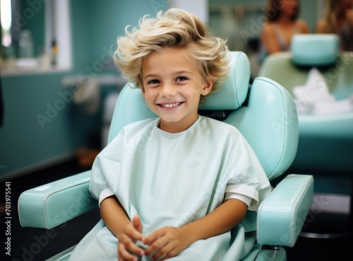 cute little boy sitting in barber chair and smiling at camera