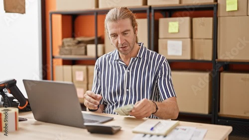 Mature businessman counting dollar bills in a warehouse office environment. photo