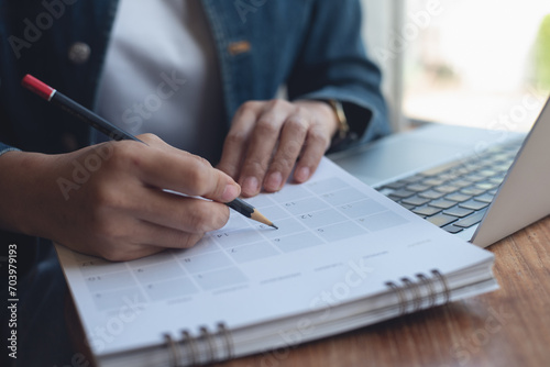 2024 Event planner timetable agenda plan on schedule event. Business woman checking planner, taking note on calendar desk on office table. Calendar event plan, work planning photo