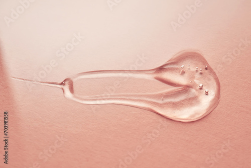 A drop of transparent cosmetic gel on a pink background.