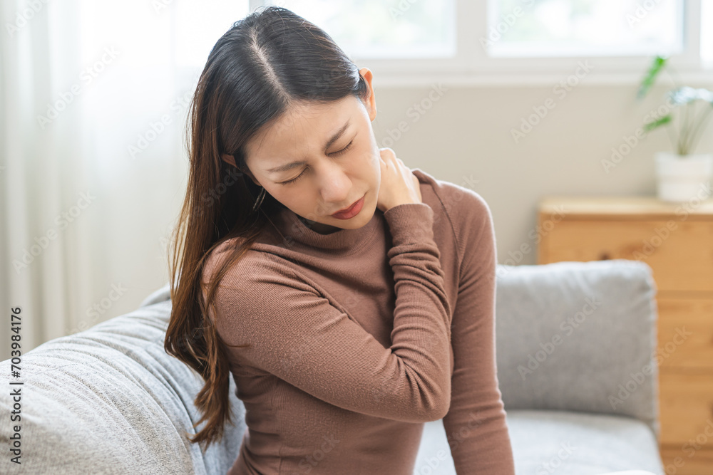 Pain body muscles stiff problem, suffer asian young woman, girl face painful, hand holding neck ache from work hand holding massaging rubbing shoulder hurt, sore sitting on couch at home. Health care Pain body muscles stiff problem, suffer asian young woman, girl face painful, hand holding neck ache from work hand holding massaging rubbing shoulder hurt, sore sitting on couch at home. Health care