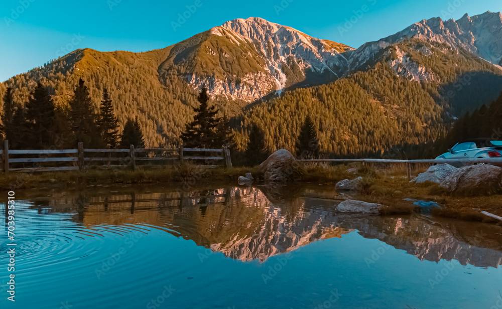 Alpine sunset or sundowner with reflections in a pond at the famous Maria Waldrast monastery, Matrei am Brenner, Innsbruck, Tyrol, Austria