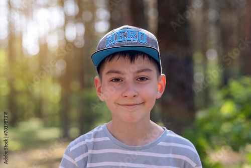 Boy 10 Years Old in a Cap Looking at the Camera Against a Background of Nature © Inna
