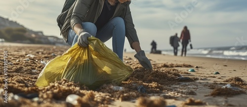 An Environmentalist Diligently Collecting Garbage in a Bag While Crouching at the Beach. Generative AI