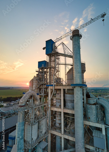 Cement plant with high factory structure and tower cranes at industrial production area. Manufacture and global industry concept