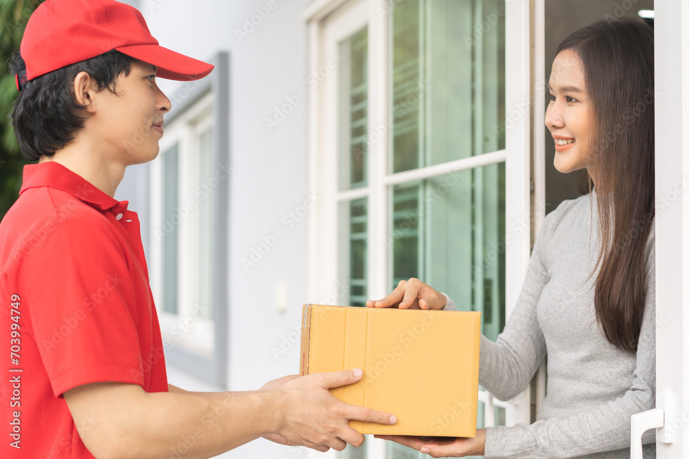 Delivery service asian young customer woman hand received cardboard box parcel from messenger male. Postman in red uniform holding cardboard box parcel, carton send to client at home, shopping online. Delivery service asian young customer woman hand received cardboard box parcel from messenger male. Postman in red uniform holding cardboard box parcel, carton send to client at home, shopping online.