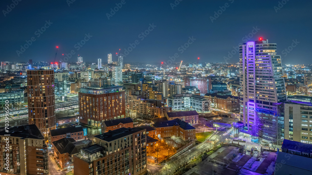 Leeds city centre, West Yorkshire United Kingdom. Aerial view looking towards the train station and city at night, illuminated city offices and buildings