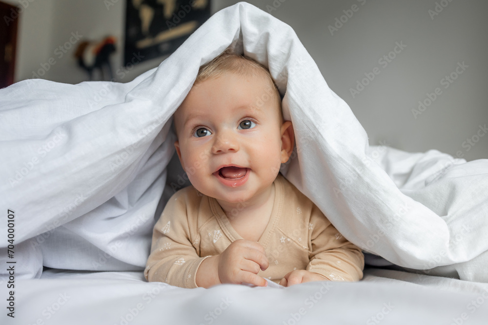Wonderful babe plays on the bed in a light sheet, hiding under a white blanket,playing with mommy hide and seek Wonderful babe plays on the bed in a light sheet, hiding under a white blanket,playing with mommy hide and seek